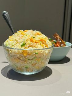 a bowl filled with rice next to another bowl full of vegetables on a table top