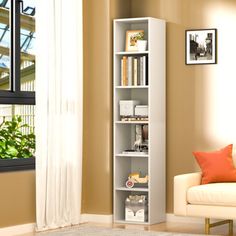 a living room with a white couch and book shelf next to a window in the corner