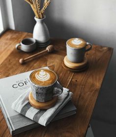 two cups of coffee sitting on top of a wooden table