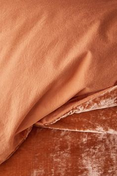 an unmade bed with orange sheets and brown pillow cases on it's sides