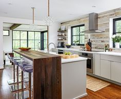 a kitchen with wooden walls and white cabinets, an island in the middle is surrounded by bar stools