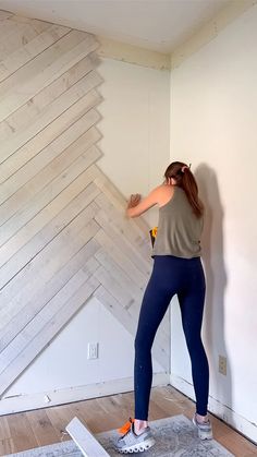 a woman standing on top of a wooden floor in front of a wall with planks