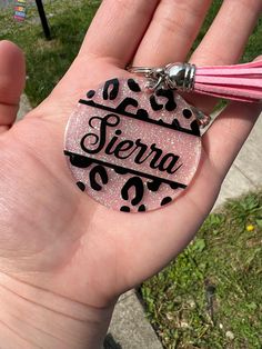 a hand holding a pink and black keychain that says sierra