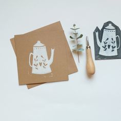 two cards with teapots on them next to a rubber stamp and a wooden spoon