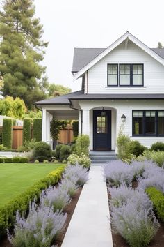 a white house with purple flowers in the front yard