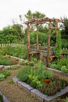 the garden is full of plants and flowers, including an arbor with trelliss