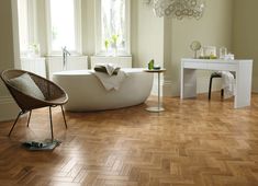 a white bath tub sitting on top of a hard wood floor next to a table