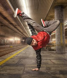 a man doing a handstand on his feet in the middle of a train station