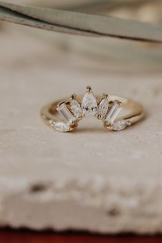 three stone engagement ring sitting on top of a piece of paper with scissors in the background