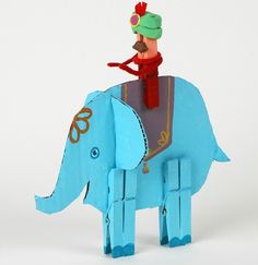 an origami elephant with a man riding on it's back and wearing a green hat