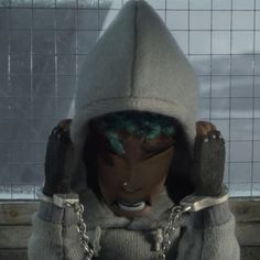 a person wearing a hoodie with chains around their ankles and hands on their head