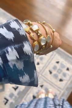 a close up of a person's arm with bracelets on it and a rug in the background