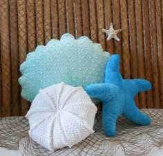 two blue and white starfish pillows sitting next to each other on top of a table