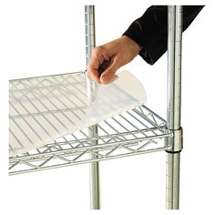 a person is holding a piece of paper on a wire shelving unit with wheels