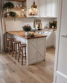 a kitchen with white cabinets and wooden counter tops, an island in between two stools