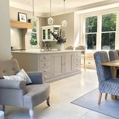 a living room filled with furniture next to a kitchen and dining room table in front of a large window