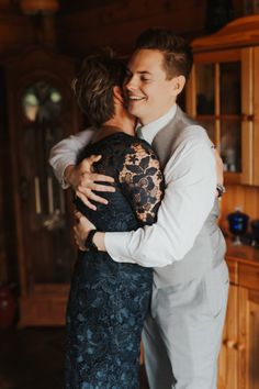 a man and woman hugging each other in front of a wooden cabinet