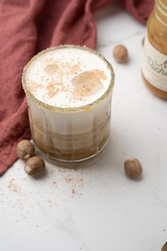 a drink sitting on top of a table next to nuts