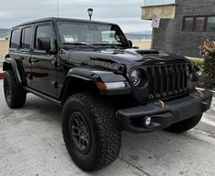 a black jeep parked in front of a building on the beach with its lights on