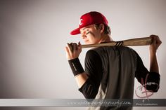 a young man holding a baseball bat over his shoulder while wearing a red hat and black shirt