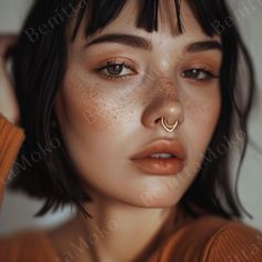 a woman with freckles on her nose and nose piercings is posing for the camera