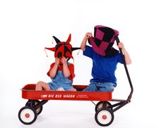 two children sitting in a wagon with hats on their heads and one holding onto the wheel