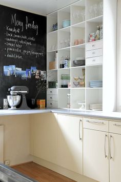 a kitchen with white cabinets and chalkboard on the wall