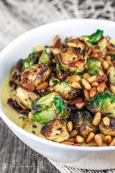 a white bowl filled with brussel sprouts and beans