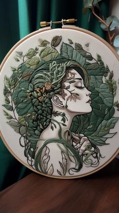 a close up of a embroidery on a table with a plant and woman's face