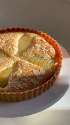 a pie on a plate with almonds and pineapple slices in the crusting