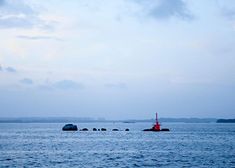 there is a red boat in the middle of the water with rocks on both sides