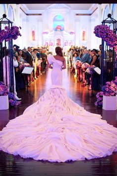 the bride is walking down the aisle in her wedding dress with purple flowers on it