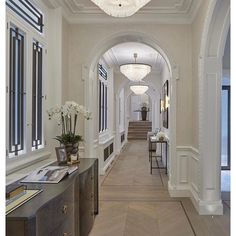 a long hallway with white walls and wood flooring on both sides is flanked by an arched doorway