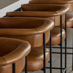 several brown leather chairs lined up against a wall