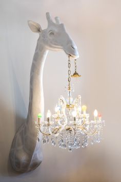 a giraffe figurine holding a chandelier in front of a wall