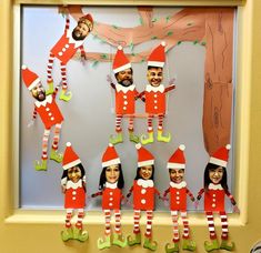 a group of elfs hanging from a tree in front of a bulletin board with pictures on it