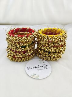 two gold and red beaded bracelets sitting on top of a white tablecloth