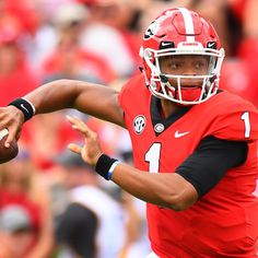 a football player is throwing the ball in front of an onlooking crowd