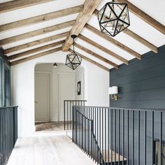 a white and blue house with wooden beams on the ceiling, wood flooring and black iron railings