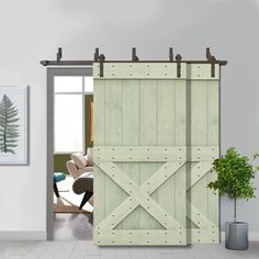 an open barn door in front of a living room with a chair and potted plant