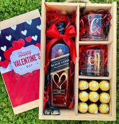 an open box with chocolates, wine and other items in it on the grass