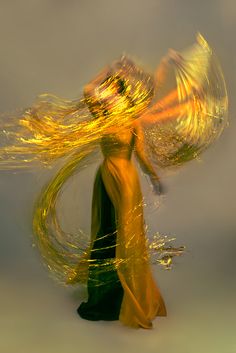 a woman in a yellow dress with her hair flying through the air and flowing around