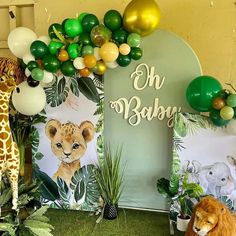 an animal themed baby shower with balloons and jungle animals on the wall, lion balloon arch