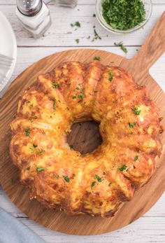 a cheesy bread is sitting on a cutting board next to other dishes and utensils