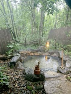 an outdoor hot tub surrounded by rocks and trees