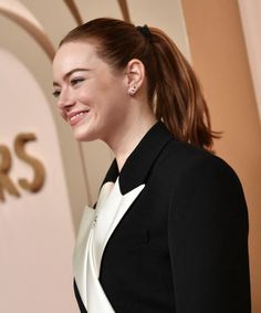 a woman in a black and white suit smiles as she stands on the red carpet