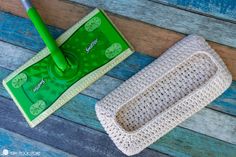 a green mop sitting on top of a wooden floor next to a cleaning sponge