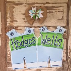 two blue and green sports jerseys hanging on a wooden door with a burlock