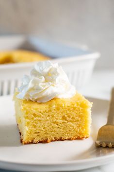 a piece of cake with whipped cream on top sits on a plate next to a fork