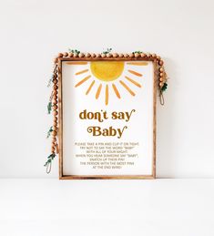 a sign that says don't say baby in front of a white wall with an orange sun